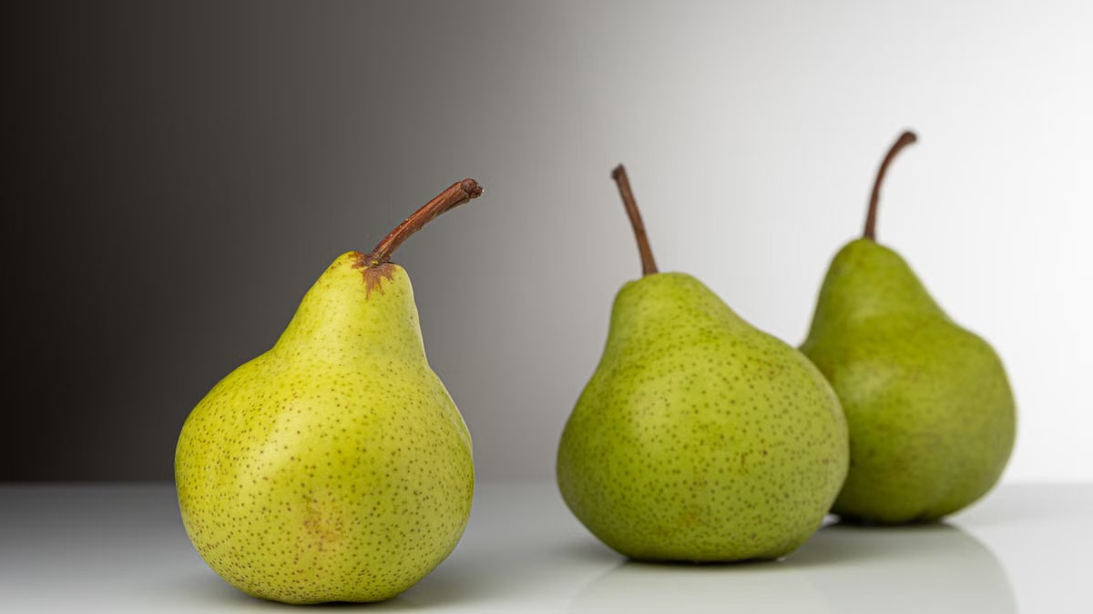 Close-up of fresh green pears on a white background, showcasing their vibrant color and texture.